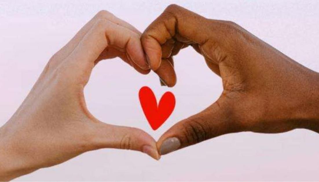 giornata-mondiale-del-cuore Due mani con diverse tonalità di pelle si uniscono per formare la sagoma di un cuore, con un piccolo cuore rosso stilizzato al centro