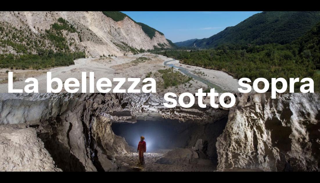 settimana-della-terra-2026 Fotomontaggio di un paesaggio diviso a metà: in alto una valle montana con un fiume e la scritta bianca "La bellezza sopra sotto sopra"; in basso una grotta sotterranea con uno speleologo in tuta rossa illuminato dalla sua torcia